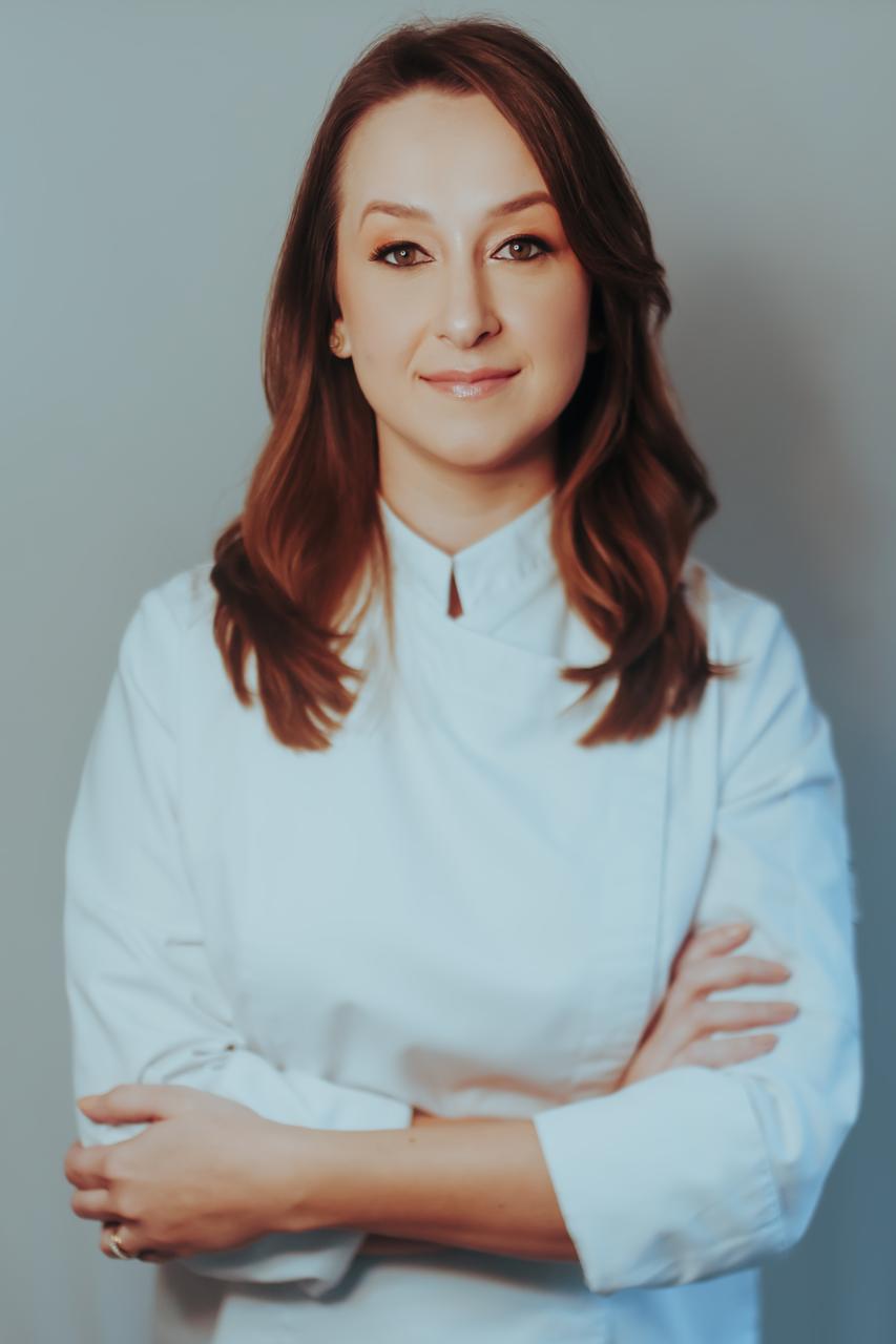Chef Patrícia Brüske de dólmã na bancada com diploma da École Lenôtre